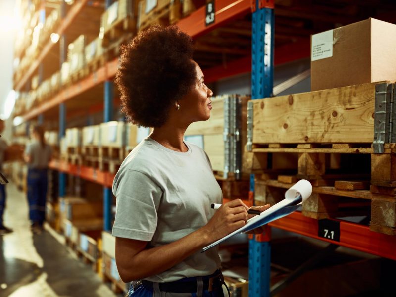 african-american-worker-writing-inventory-list-while-checking-stock-storage-room
